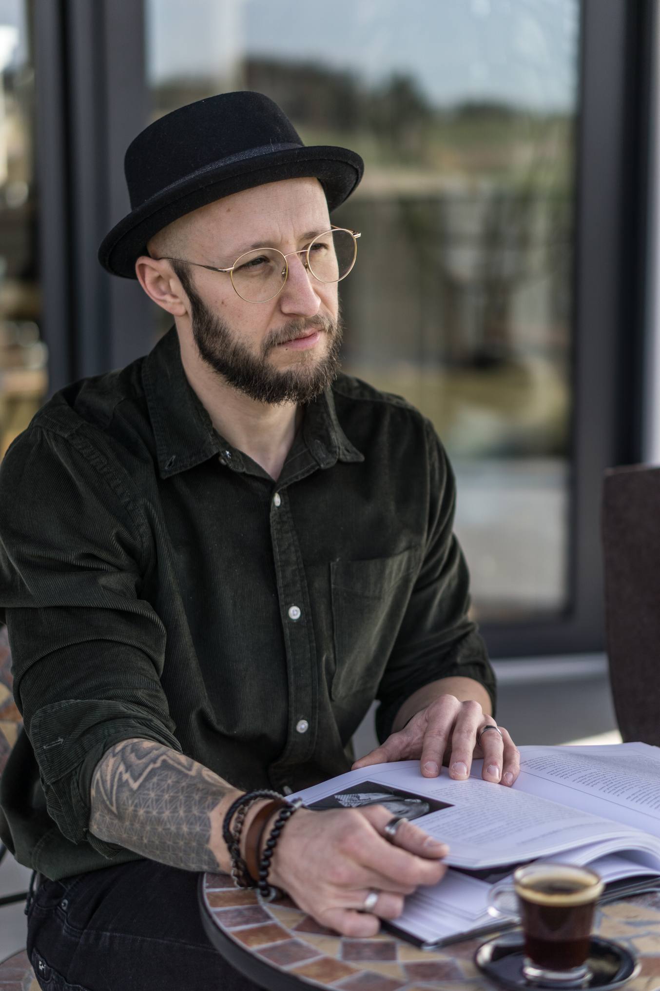 Mann mit Hemd und Hut sitzt an einem Tisch und liest